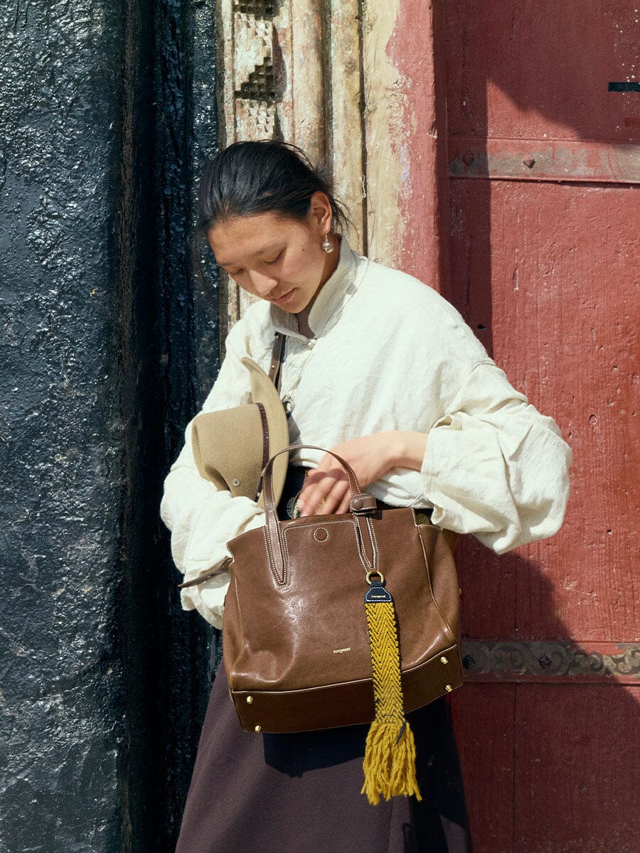 Songmont Small Yore Duffle Bag Sandal - carried by hand with a yellow tassel