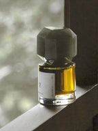 TO SUMMER Void Eau de Parfum bottle glowing amber in window light