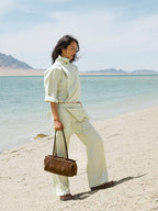 Songmont Yore Baguette Bag Sandal held by hand on the beach