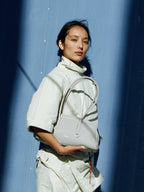 Songmont Yore Toast Bag Celeste - carried in the crook of the arm against a blue wall