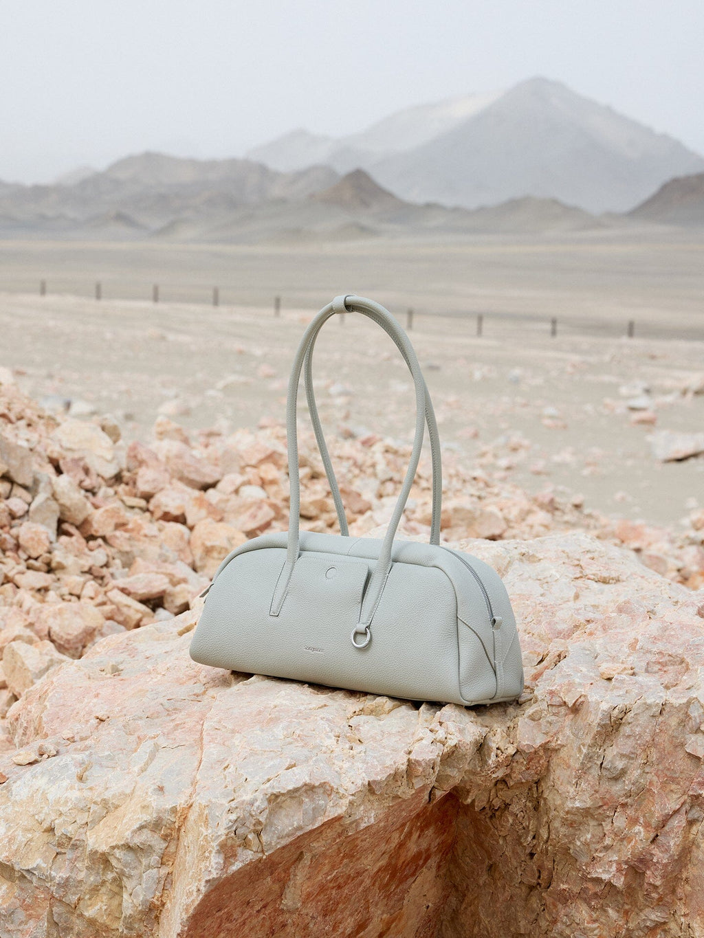Songmont Yore Toast Bag Celeste - bag resting on a rock in a mountain landscape