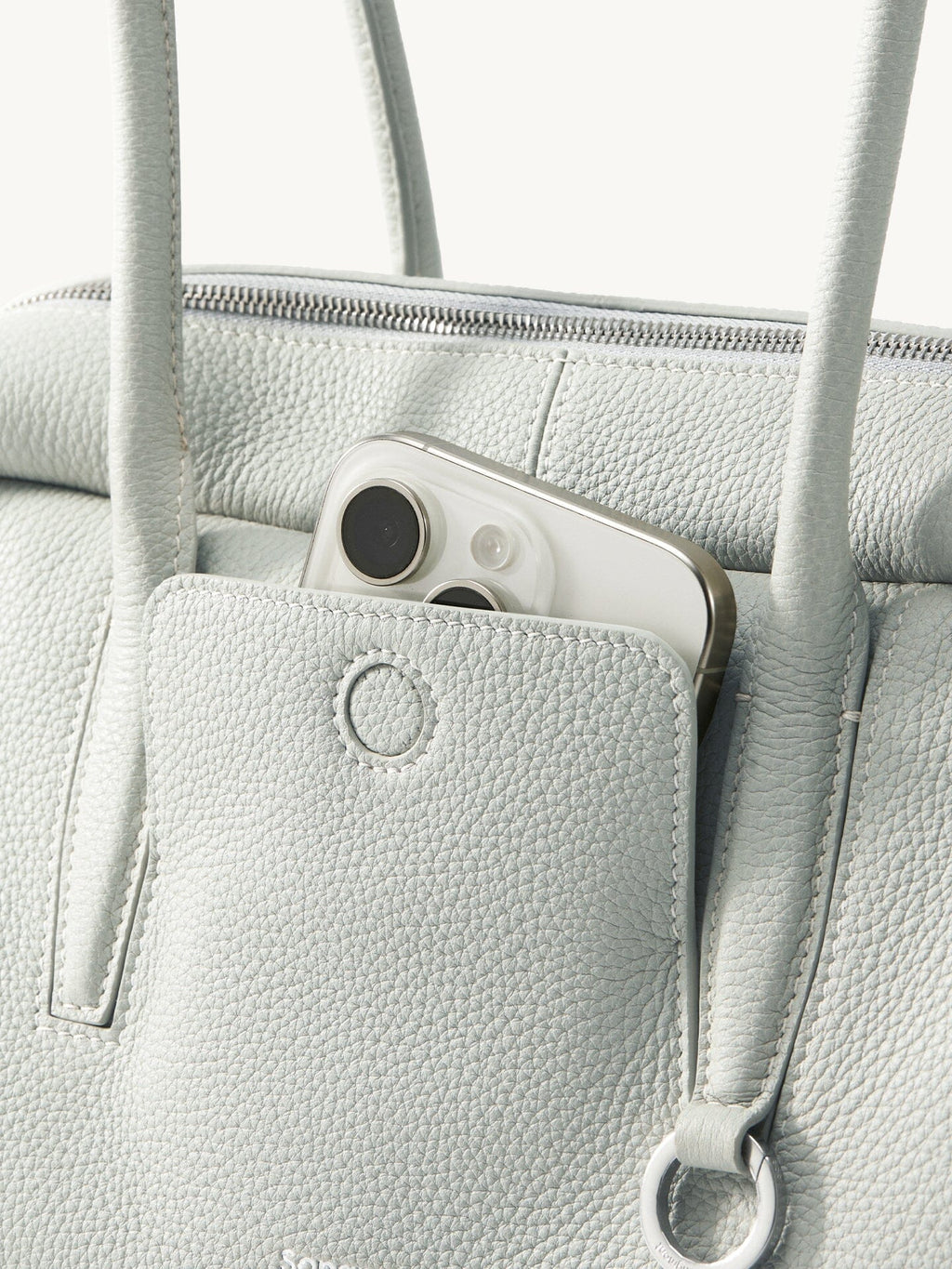Songmont Yore Toast Bag Celeste - front slip pocket holding a phone, metal ring detail