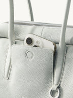 Songmont Yore Toast Bag Celeste - front slip pocket holding a phone, metal ring detail
