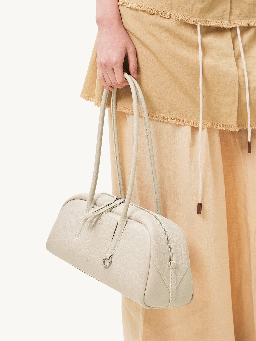 Songmont Yore Toast Bag Cloud - held by the handles beside a linen skirt