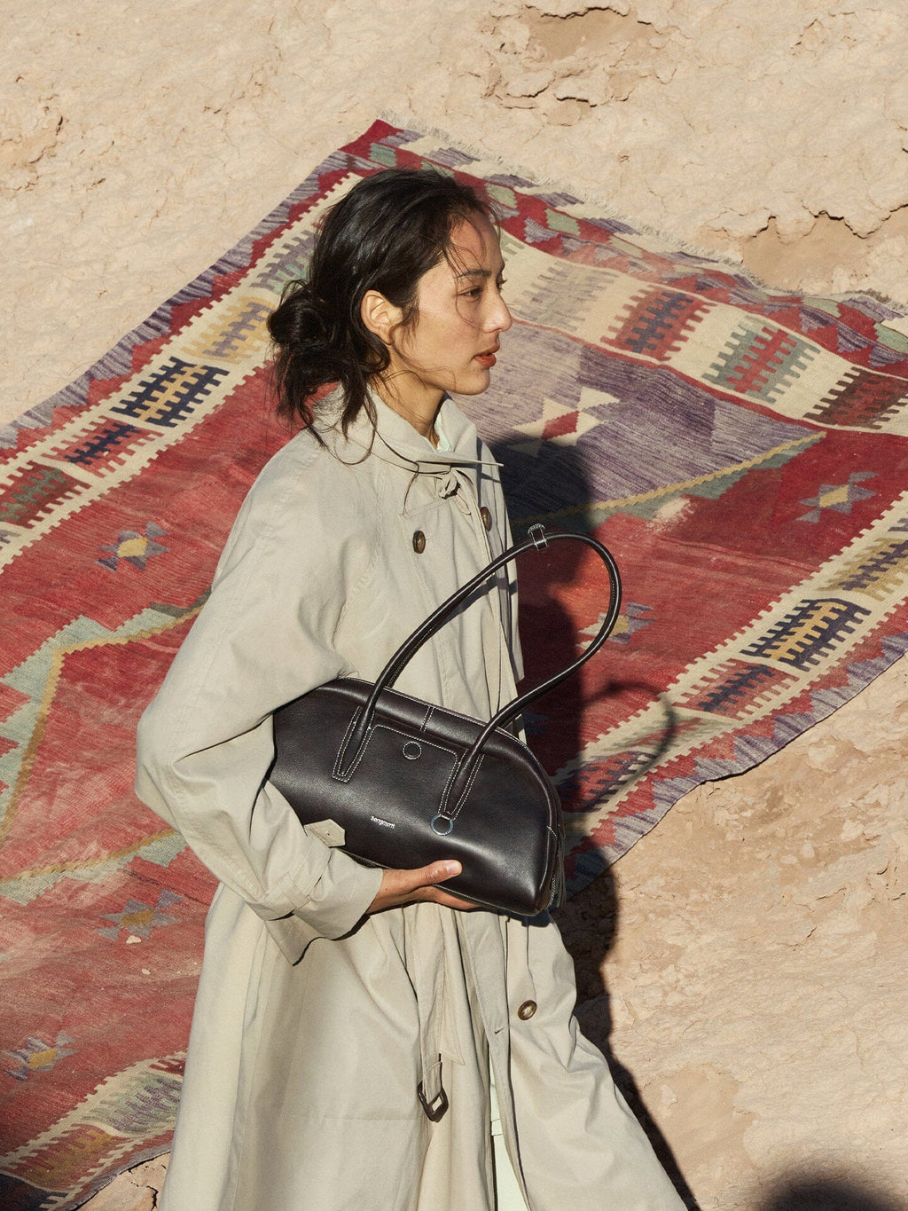 Songmont Yore Toast Bag Ebony - held under the arm against a patterned rug