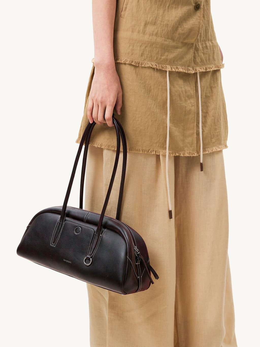 Songmont Yore Toast Bag Ebony - held by the handles beside a linen skirt