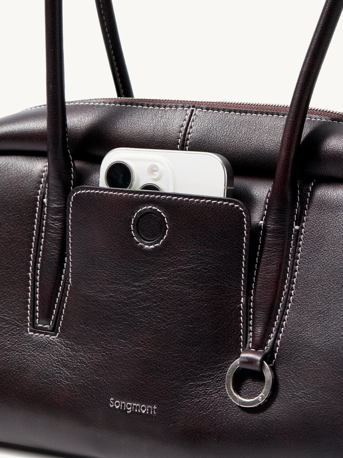 Songmont Yore Toast Bag Ebony - front slip pocket holding a phone, metal ring detail